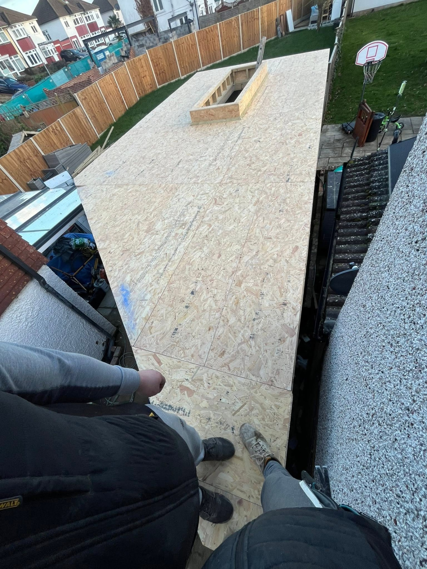 Carpenters installing timber roof framework and OSB sheathing on a residential extension