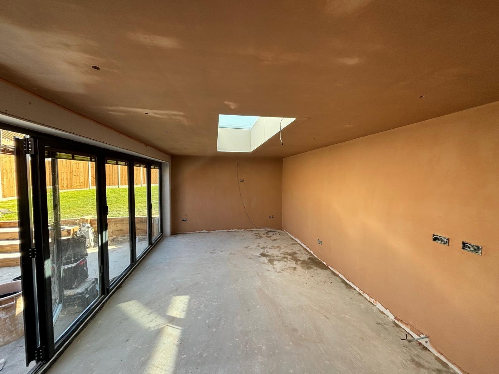 Newly plastered home extension interior with bifold doors and roof lantern
